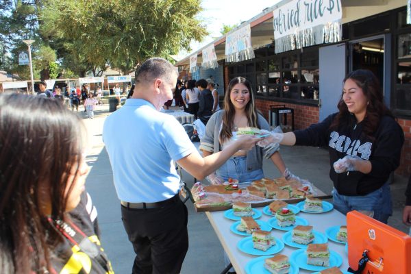 Dr. Ortiz supports ASB by purchasing a Titos sandwich from Krissia Valle as Kim Garcia looks on.